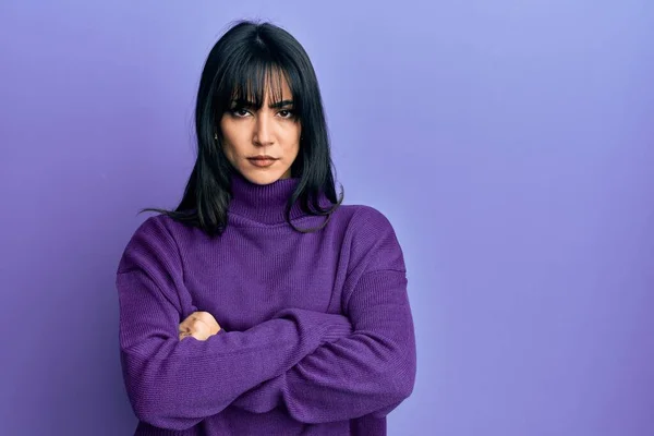 Young brunette woman with bangs wearing turtleneck sweater skeptic and nervous, disapproving expression on face with crossed arms. negative person.