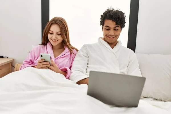 Casal Jovem Sorrindo Feliz Usando Laptop Smartphone Quarto — Fotografia de Stock