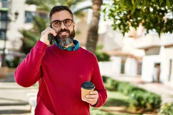 Young hispanic executive man talking on the smartphone drinking coffee at the city.