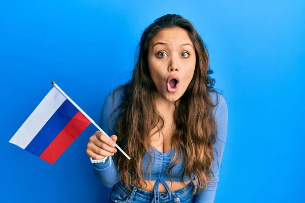 年轻的惊慌失措的女孩举着俄罗斯国旗 惊慌失措 张大嘴巴惊愕不已 不敢相信自己的脸 — 图库照片
