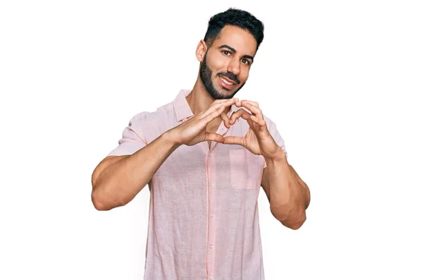 一个留着胡子的西班牙男人 穿着休闲装 带着爱心微笑 用手做着心形符号 浪漫的概念 — 图库照片