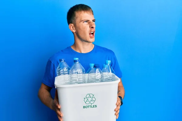 プラスチック製のボトルでリサイクルゴミ入れを保持している若い白人男性は怒りで叫び フラストレーションと激怒し 怒って叫びました 怒りと攻撃的な考え方 — ストック写真