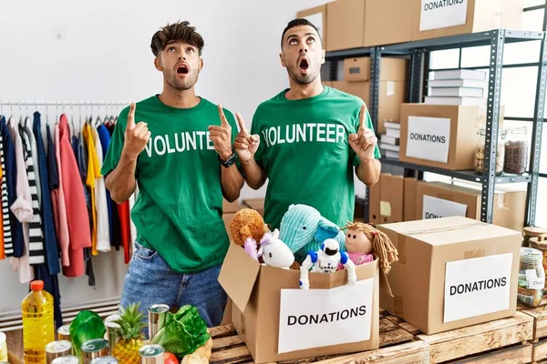 Joven Pareja Gay Vistiendo Camiseta Voluntaria Donaciones Stand Asombrado Sorprendido —  Fotos de Stock