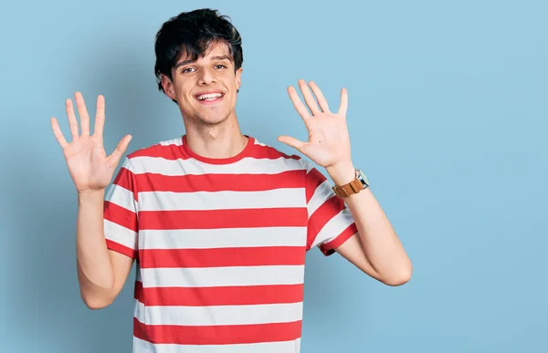自信と幸せ笑顔ながらカジュアルなストライプのTシャツを身に着けているハンサムなヒップスター若い男が現れ 指の番号10で指摘します — ストック写真