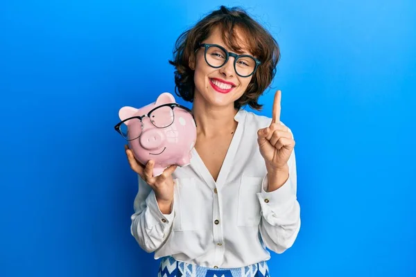 Jonge Brunette Vrouw Holding Piggy Bank Met Bril Glimlachen Met — Stockfoto