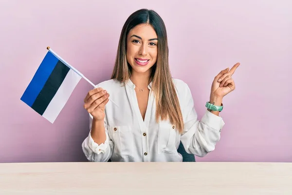 Young Hispanic Woman Holding Estonia Flag Sitting Table Smiling Happy — Stock Photo, Image