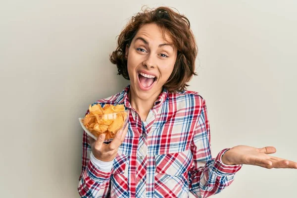 Young Brunette Woman Holding Potato Chips Celebrating Achievement Happy Smile — Stock Photo, Image