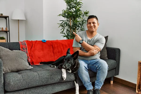 Jovem Latino Homem Cão Sentado Sofá Casa Apontando Com Dedo — Fotografia de Stock