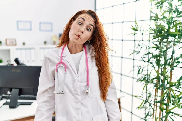 Mujer Pelirroja Joven Vistiendo Uniforme Médico Estetoscopio Clínica Haciendo Cara —  Fotos de Stock