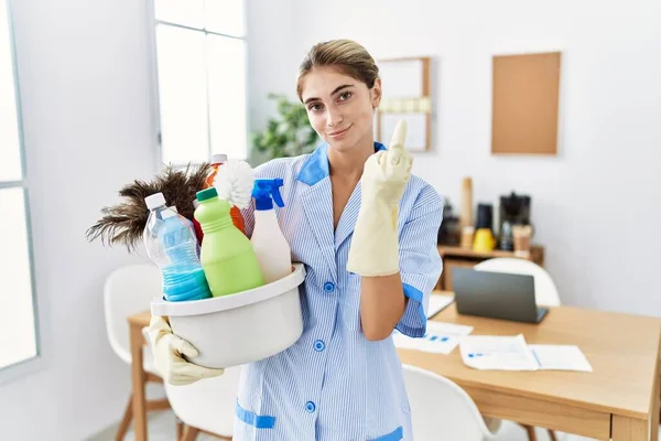 Young Blonde Woman Wearing Cleaner Uniform Holding Cleaning Products Showing — стоковое фото