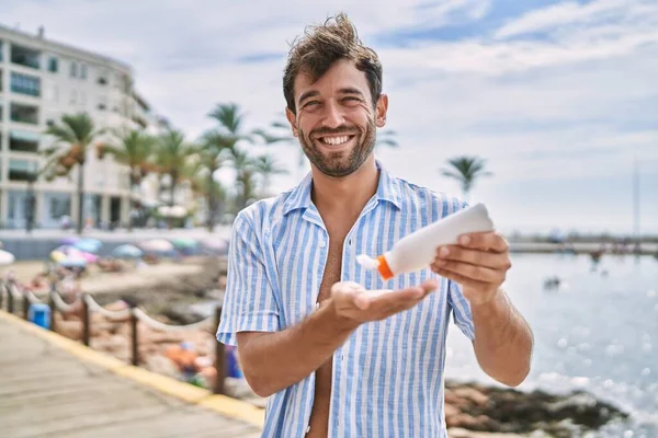 Ung Latinamerikansk Man Ler Glad Med Solkräm Lotion Stranden — Stockfoto