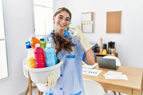 Jovem Loira Vestindo Uniforme Limpeza Segurando Produtos Limpeza Sorrindo Alegre — Fotografia de Stock