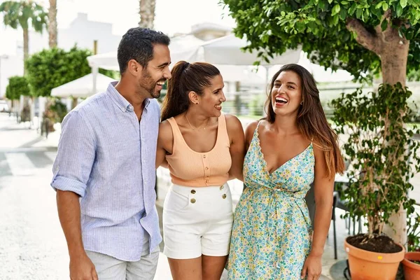 Üç İspanyol arkadaş şehirde mutlu bir şekilde gülüyor ve sarılıyorlar..