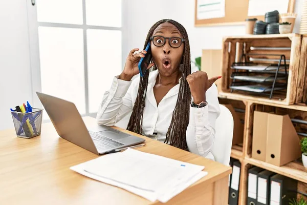 Черная Женщина Косичками Работает Офисе Разговаривая Телефону Удивлен Показывая Пальцем — стоковое фото