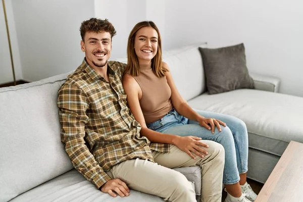 Jovem Casal Hispânico Sorrindo Feliz Abraçando Sentado Sofá Casa — Fotografia de Stock