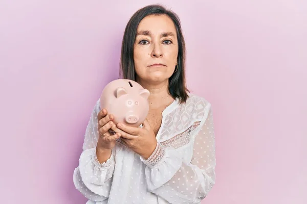 Mulher Hispânica Meia Idade Segurando Mealheiro Relaxado Com Expressão Séria — Fotografia de Stock