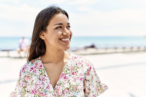 Young latin girl smiling happy standing at the beach.