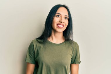 Gündelik tişört giyen genç İspanyol kız yüzünde gülümsemeyle yan yana bakıyor, doğal bir ifade. Kendinden emin gülen. 