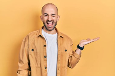 Genç kel adam avuçlarını açmış, elinde bir şey tutuyor kameraya seksi bir ifadeyle bakıyor, neşeli ve mutlu bir yüz.. 