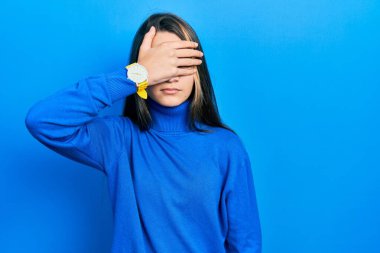 Balıkçı yaka kazak giyen genç esmer kız gözlerini eliyle kapatıyor, ciddi ve üzgün görünüyor. Görme, saklama ve reddetme konsepti 