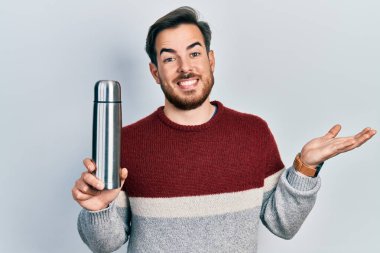 Sakallı yakışıklı beyaz adam başarıyı mutlu bir gülümsemeyle ve elini kaldırarak kutluyor. 