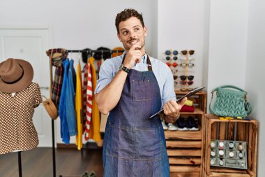 Perakende mağazasının müdürü olarak çalışan yakışıklı genç bir adam. Elleri çenesinde, soru sormayı düşünüyor. Düşünceli bir ifade. Gülümseyen ve düşünceli bir yüz. şüphe kavramı. 