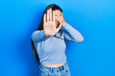 Genç esmer genç, sıradan bir süveter giyiyor, elleriyle gözlerini kapatıyor ve üzgün ve korku ifadeleriyle jest yapıyor. utangaç ve olumsuz kavram. 