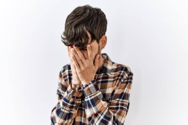 Sakallı İspanyol bir adam izole bir arka planda duruyor. Ağlarken suratını ellerle kapatıyor. depresyon kavramı. 