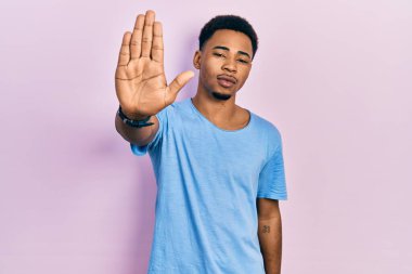 Sıradan mavi tişörtler giyen genç Afro-Amerikan bir adam avucunun içinde şarkı söylemeyi kesiyor. Yüzünde olumsuz ve ciddi bir jest olan uyarı ifadesi. 