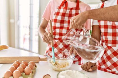 Mutlu gülümseyen genç çift mutfakta ev yapımı ekmek yapmak için su döküyor..