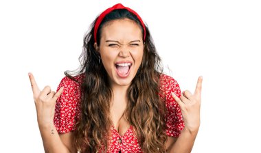 Günlük kıyafetler giymiş, çılgın bir ifadeyle bağıran genç İspanyol kız elleri havada rock sembolü yapıyor. Müzik yıldızı. ağır kavram. 