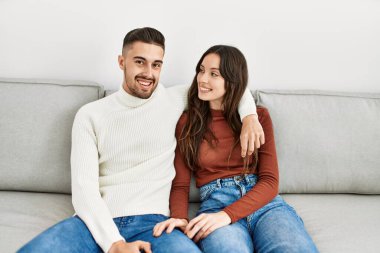 Genç İspanyol çift kanepede oturuyor ve evde sarılıyorlar..