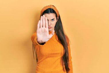 Sarı kazak giyen genç esmer kız avucunun içi gibi şarkı söylemeyi kesiyor. Yüzünde olumsuz ve ciddi bir jest olan uyarı ifadesi. 