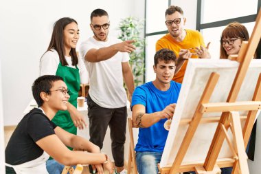 Mutlu gülümseyen ve ortak arayan bir grup insan sanat stüdyosunda..