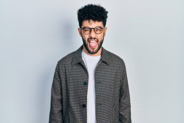 Sakallı, gözlüklü, dilini dışarı çıkaran, neşeli ifadeli genç bir Arap. duygu kavramı. 