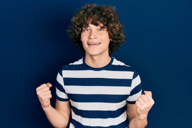 Sıradan çizgili tişört giyen yakışıklı genç adam kollarını kaldırarak ve açık gözlerle başarının şaşkınlığını ve şaşkınlığını yaşıyor. Kazanan konsept. 