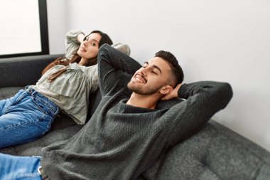 Genç İspanyol çift evde kanepede elleri üzerinde dinleniyor..