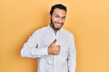 Sakallı, iş gömleği giyen İspanyol bir adam elleriyle mutlu bir jest yapıyor. Kameraya bakıp başarıyı gösteren ifade. 