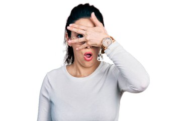 Gündelik kıyafetler giyen genç İspanyol kadın şok içinde yüzünü ve gözlerini kapayarak utanmış ifadesiyle parmaklarının arasından bakıyor.. 