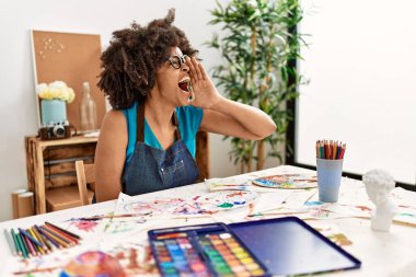 Güzel Afro saçlı Amerikalı kadın sanat stüdyosunda resim yapıyor ve el ele tutuşup bağırıyor. iletişim konsepti. 