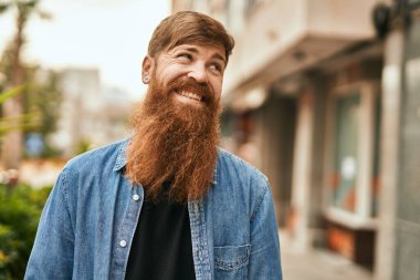 Genç İrlandalı hippi gülümseyerek şehirde mutlu mesut duruyor..