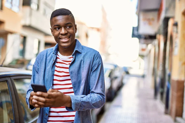 Młody Afrykanin Uśmiecha Się Szczęśliwy Korzystając Smartfona Mieście — Zdjęcie stockowe