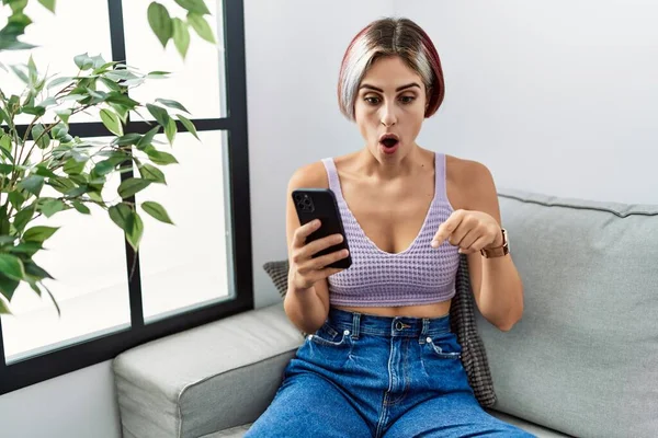 Young Beautiful Woman Using Smartphone Typing Message Sitting Sofa Pointing — Stock Photo, Image