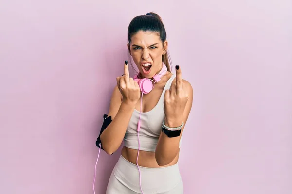 Young Hispanic Woman Wearing Gym Clothes Using Headphones Showing Middle — Fotografia de Stock