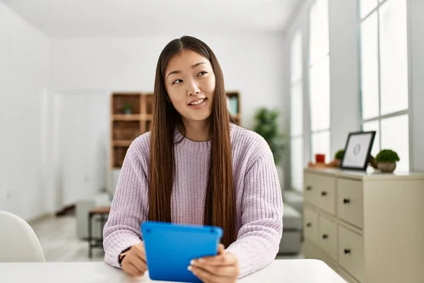 若いです中国の女の子使用してTouchpad座っていますザテーブルの上にホーム — ストック写真