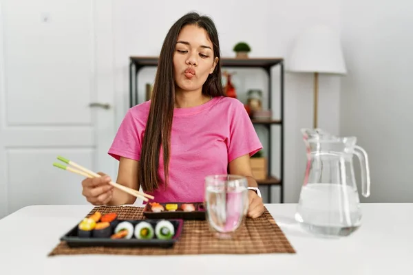 若いブルネットの女性は 狂気とコミカルなジェスチャーで魚の顔を作る箸を使用して寿司を食べる 面白い表現 — ストック写真