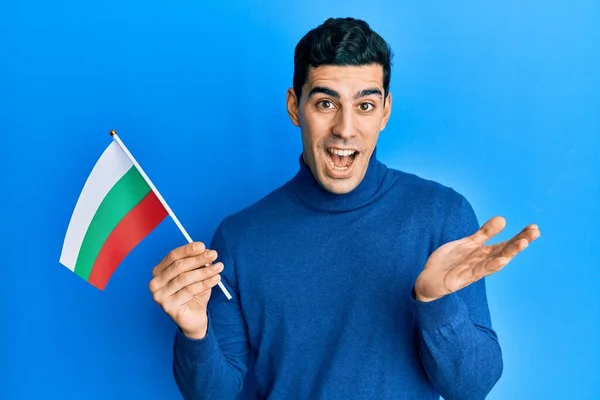 幸せな笑顔で達成を祝うブルガリアのフラグを保持し 手を上げと勝者の式 — ストック写真