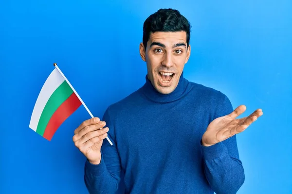 Bonito Homem Hispânico Segurando Bandeira Búlgara Celebrando Realização Com Sorriso — Fotografia de Stock