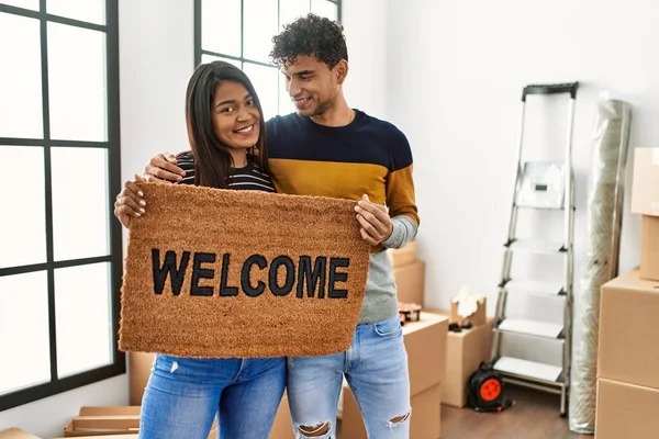 Joven Pareja Latina Sonriendo Feliz Sosteniendo Felpudo Bienvenida Nuevo Hogar —  Fotos de Stock