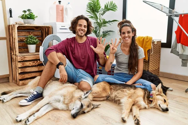 Jovem Casal Hispânico Fazendo Lavanderia Com Cães Mostrando Apontando Para — Fotografia de Stock